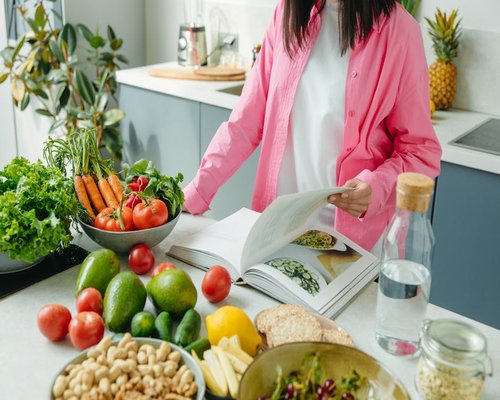 A young smiling woman preparing a fresh plant-based meal in her bright kitchen